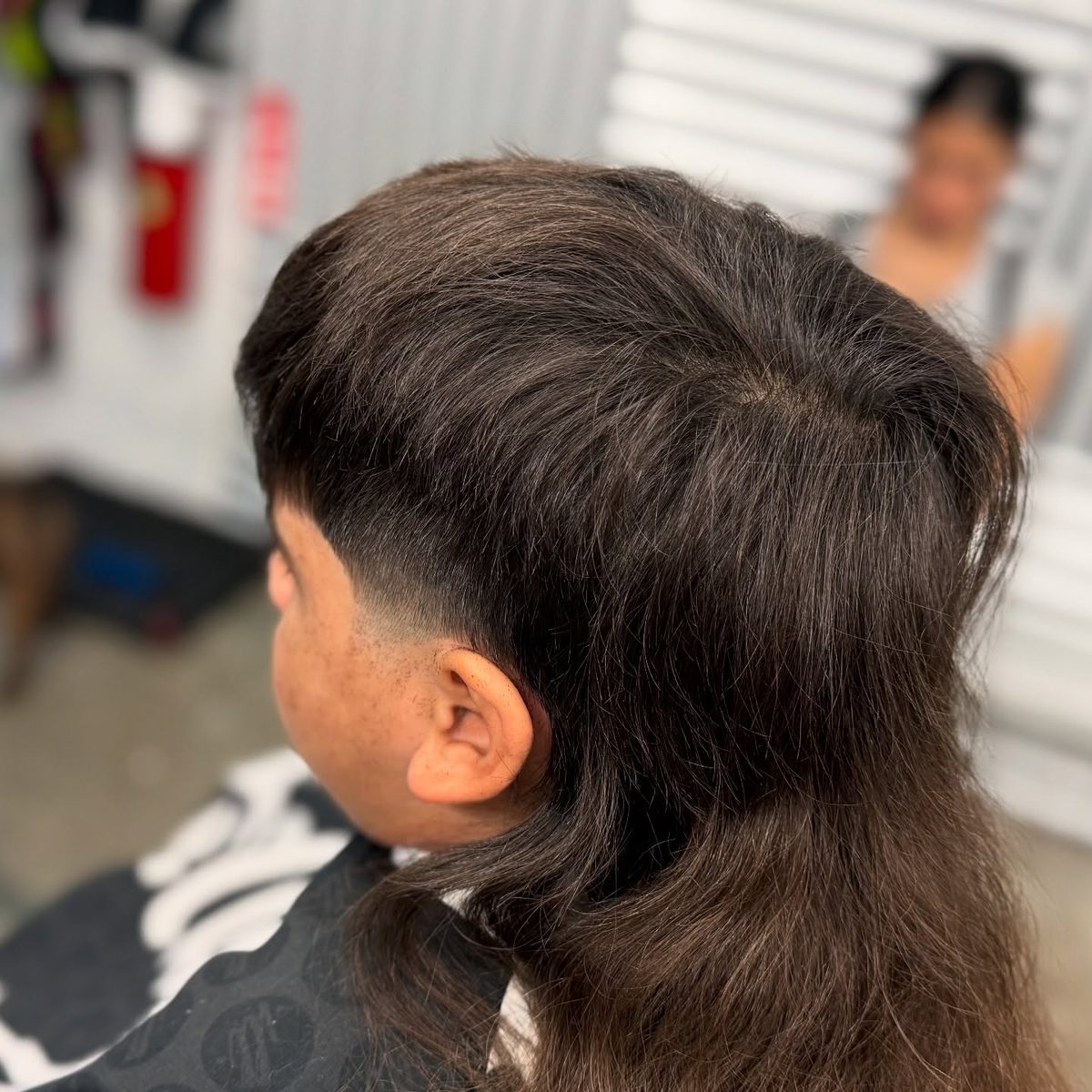 Back view of a client with a tapered cut and long hair on top